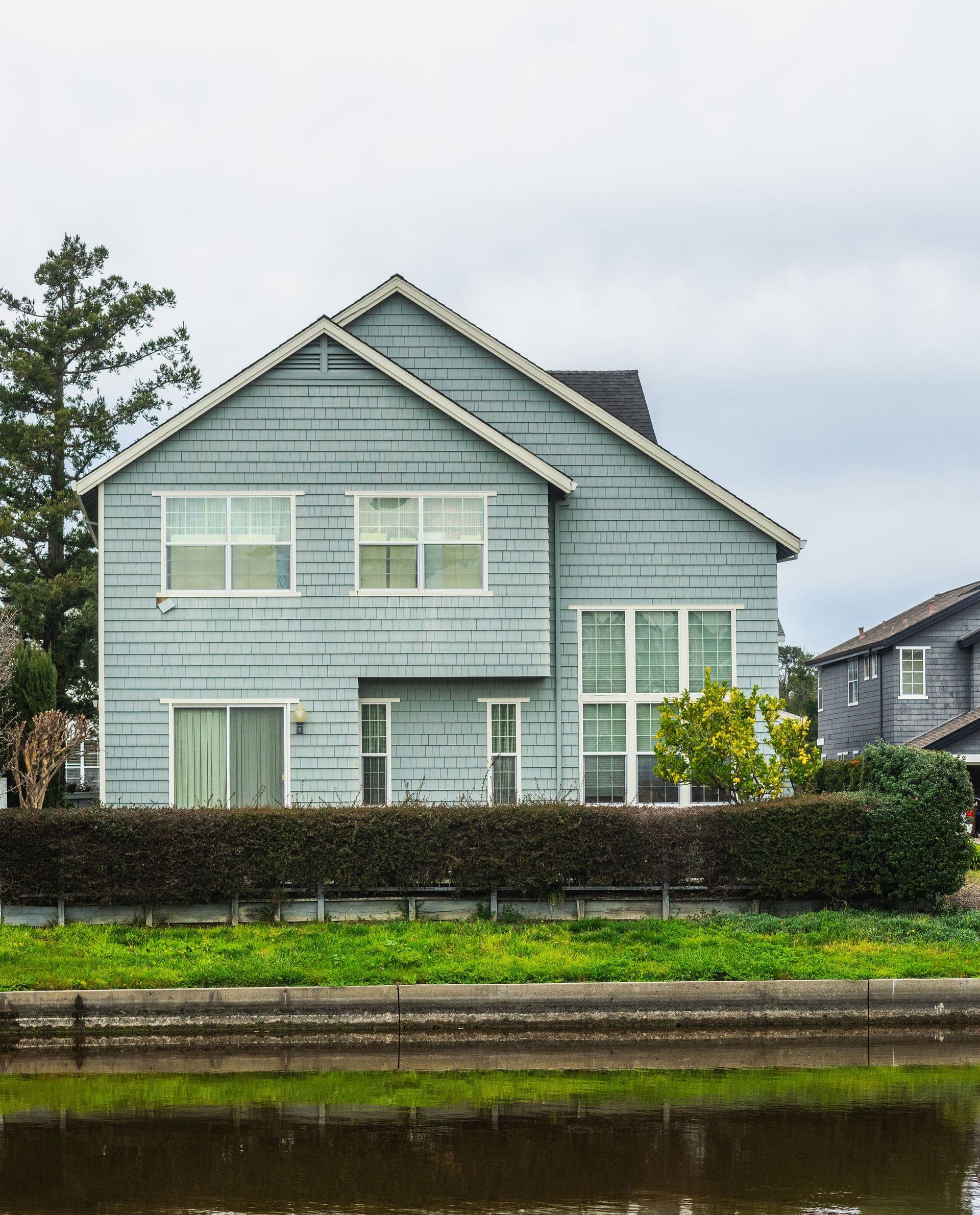 A two-story home clad in blue-gray shake siding with white-trimmed windows